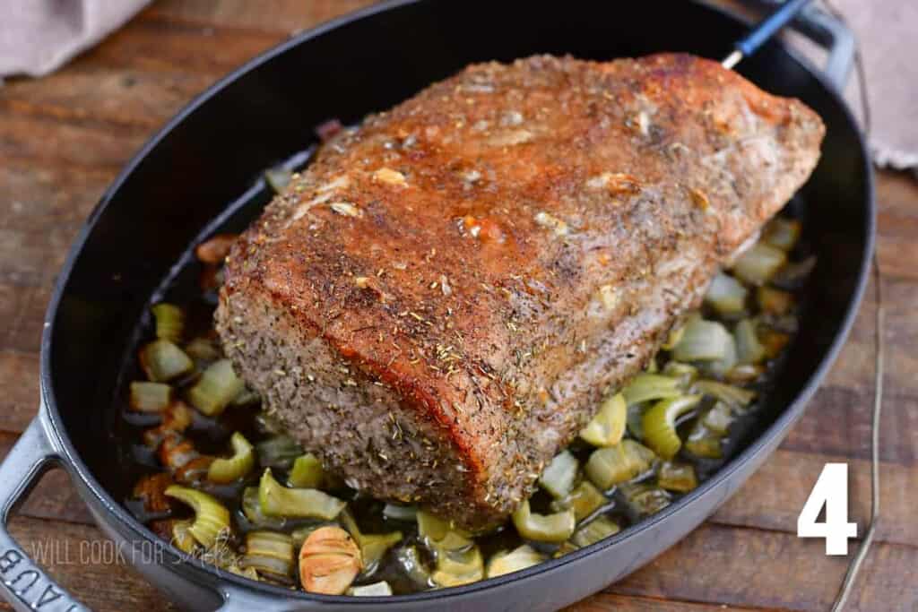 cooked garlic pork loin on veggies in the roasting pan.