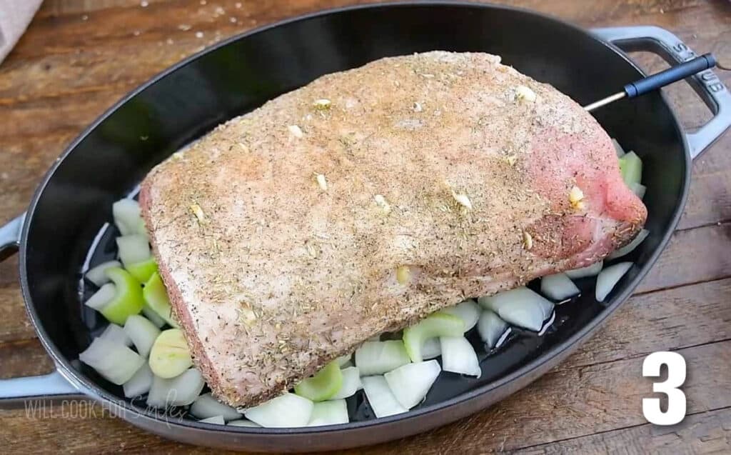 seasoned uncooked pork loin resting on the chopped vegetables in the roasting pan.
