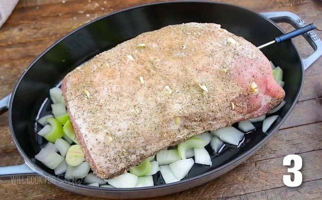 seasoned uncooked pork loin resting on the chopped vegetables in the roasting pan.