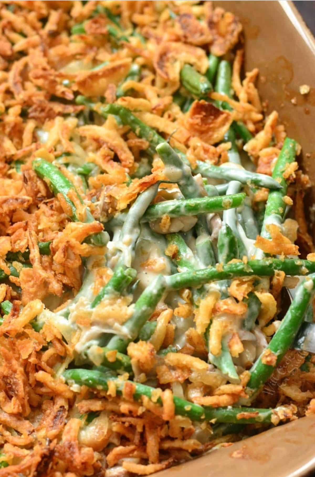 green bean casserole in a baking dish with spoon sitting in the dish.