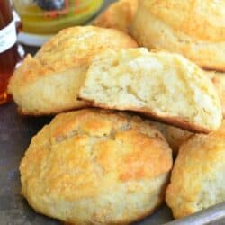 honey butter biscuits with on a baling sheet with one cut in half and honey also on the baking sheet.