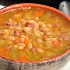 ham and bean soup in a bowl with a black spoon to the right of the bowl.