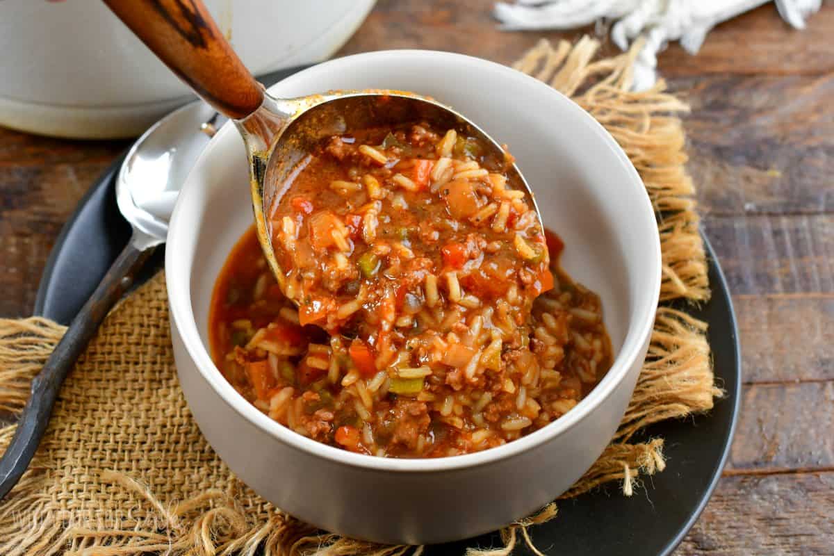 pouring stuffed pepper soup into a bowl with a big spoon.