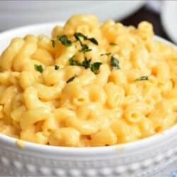 white bowl filled with creamy mac and cheese and topped with parsley.