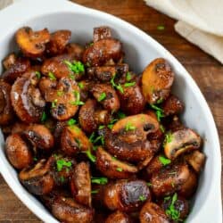 roasted mushrooms in a serving dish on a white surface.