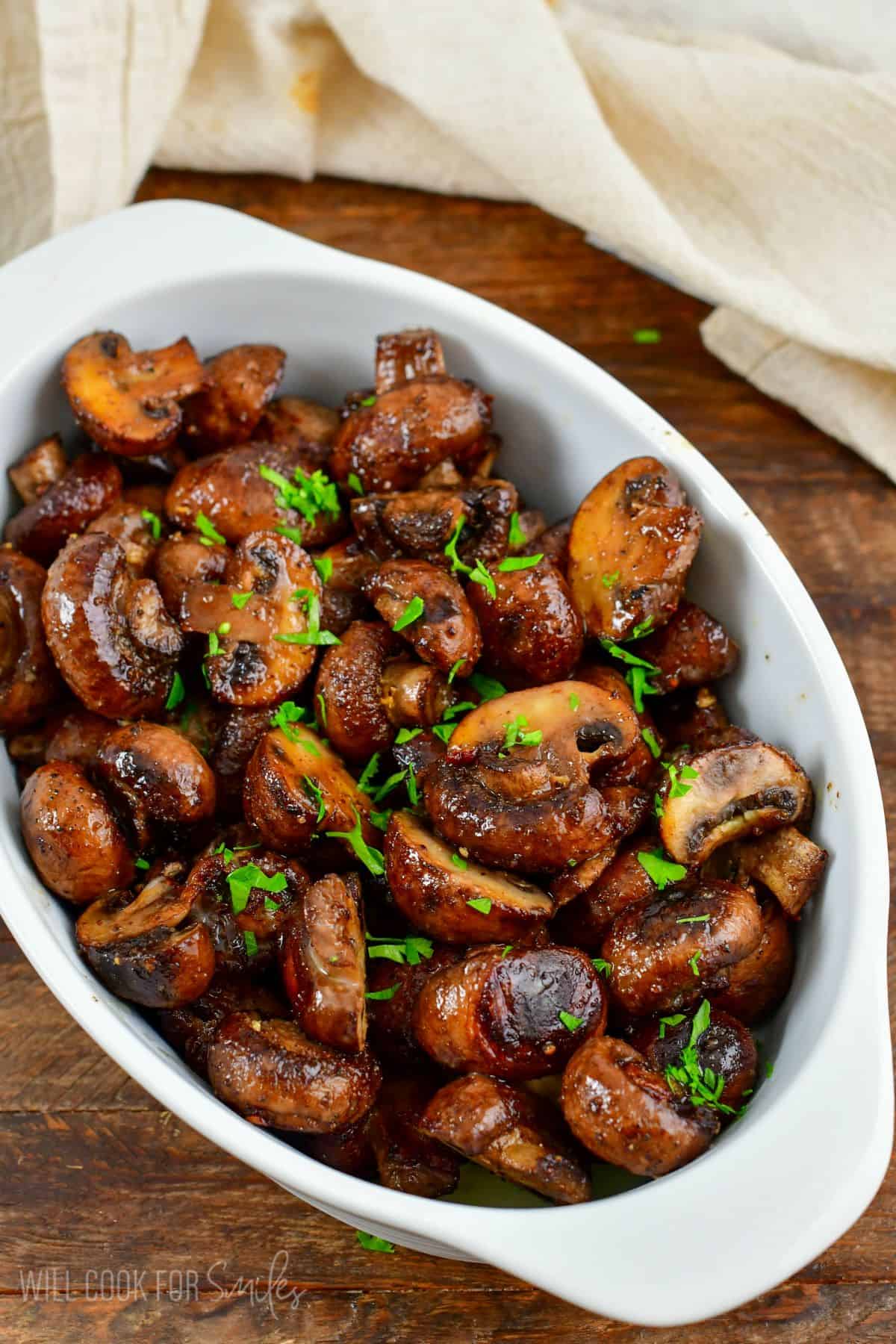 roasted mushrooms in a serving dish on a white surface.