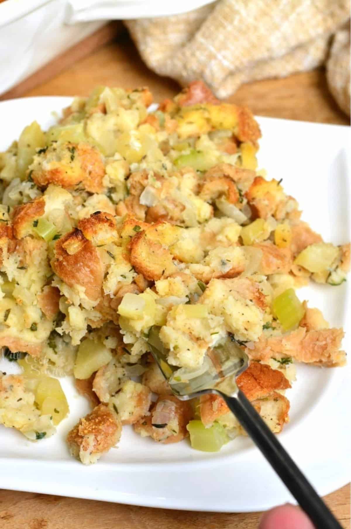 simple stuffing on a white plate with a fork taking some out.