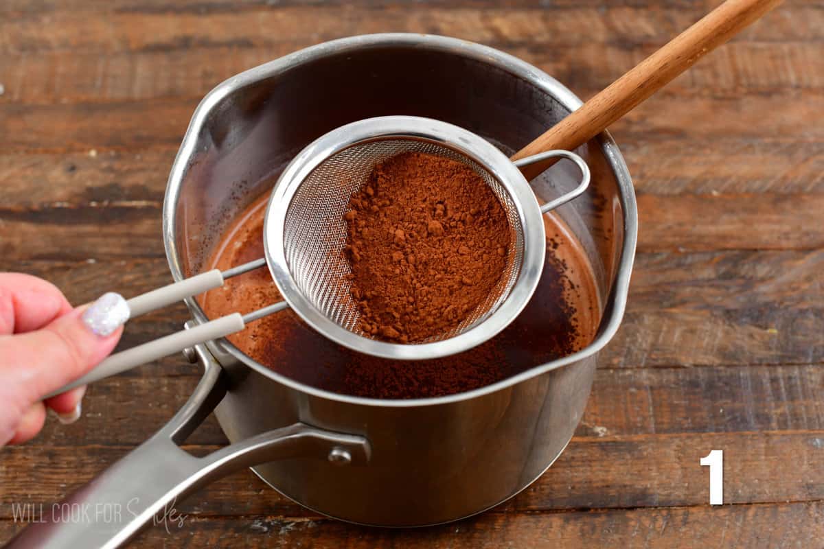 sifting the coco powder into a pot of milk.