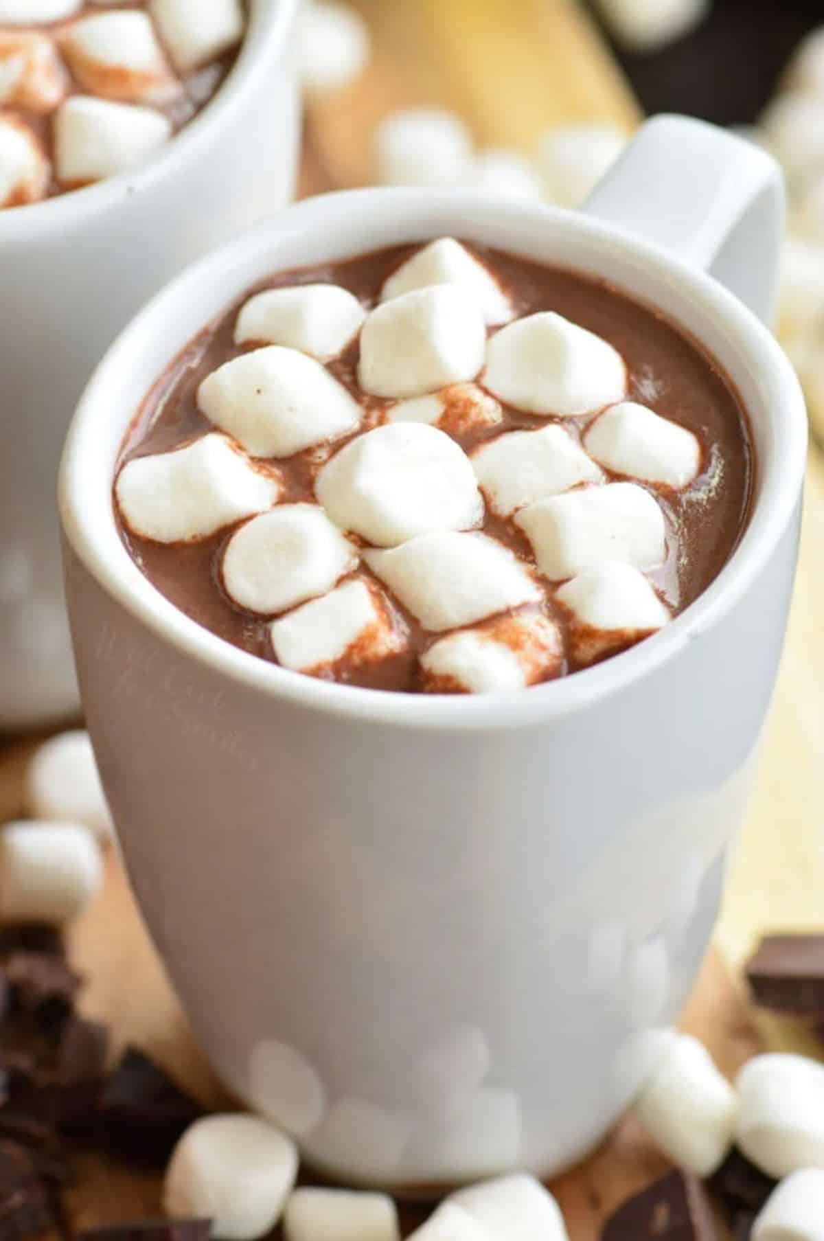 hot chocolate in a mug with marshmallows on top and around the bottom of the cup.