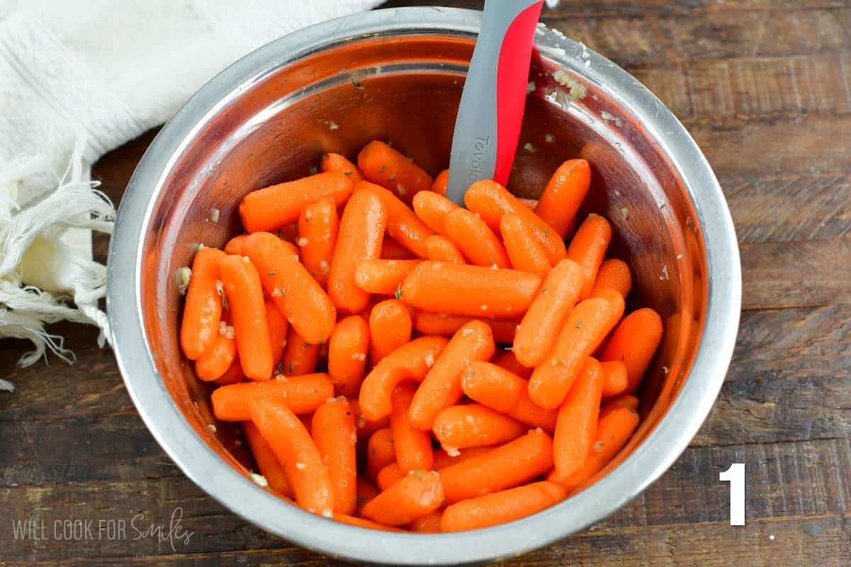 mixing baby carrots in vinegar mixture in a mixing bowl.