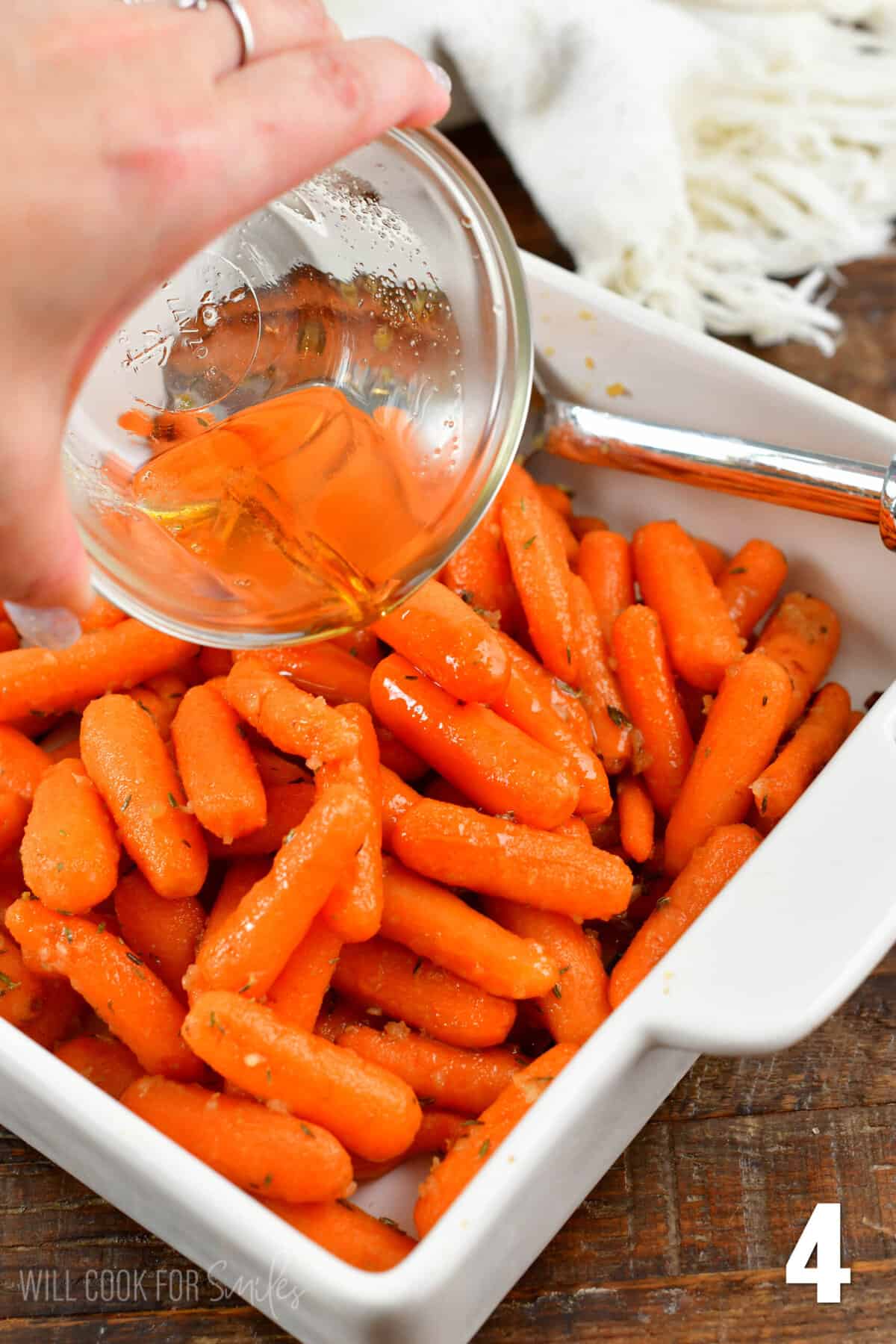 pouring balsamic glaze over the roasted carrots.