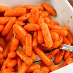 some glazed roasted carrots on a spoon over the baking dish.