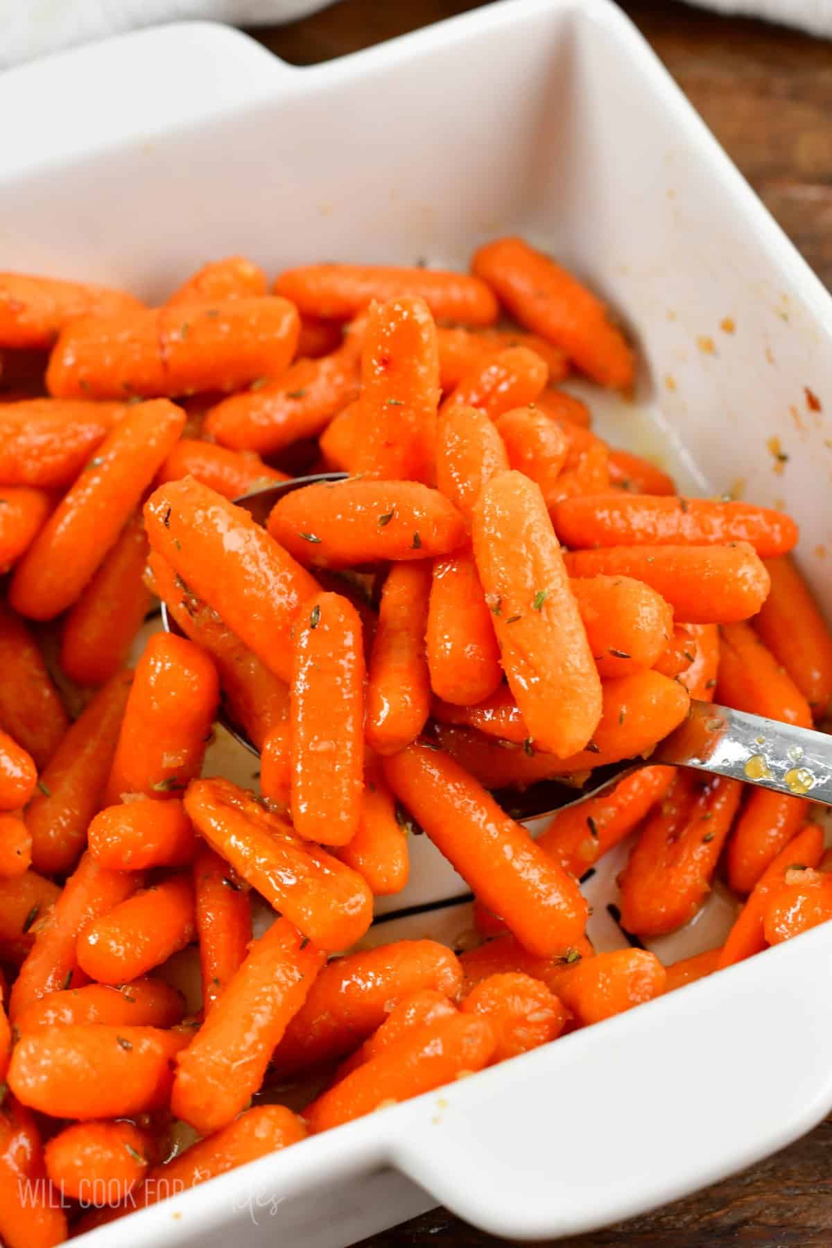 some glazed roasted carrots on a spoon over the baking dish.