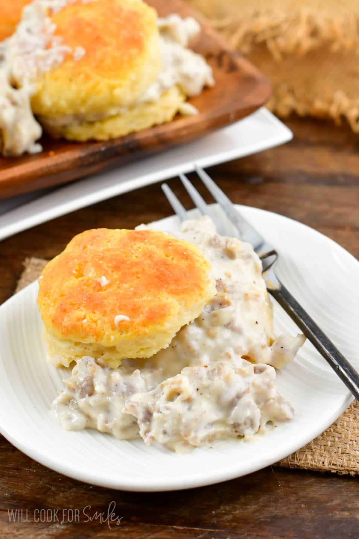 Biscuits and gravy on a plate with a fork to the right.