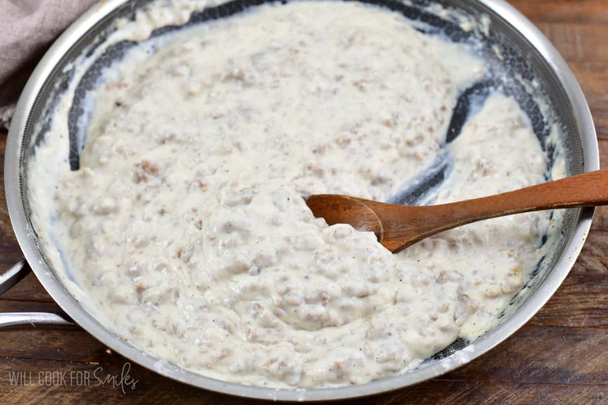 sausage gravy in a pan with a wooden spoon.