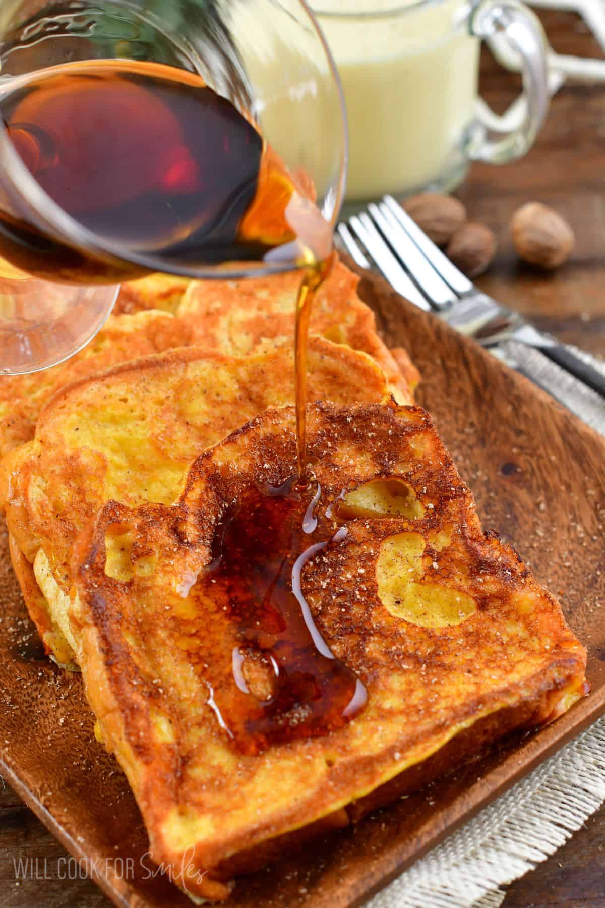 Eggnog French Toast on a plate with syrup being poured over the top.