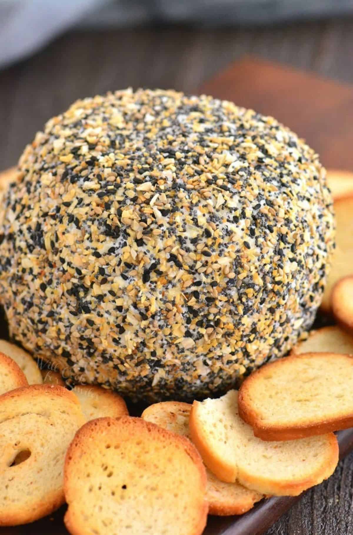 big round cheese ball coated in everything bagel seasoning with bread.
