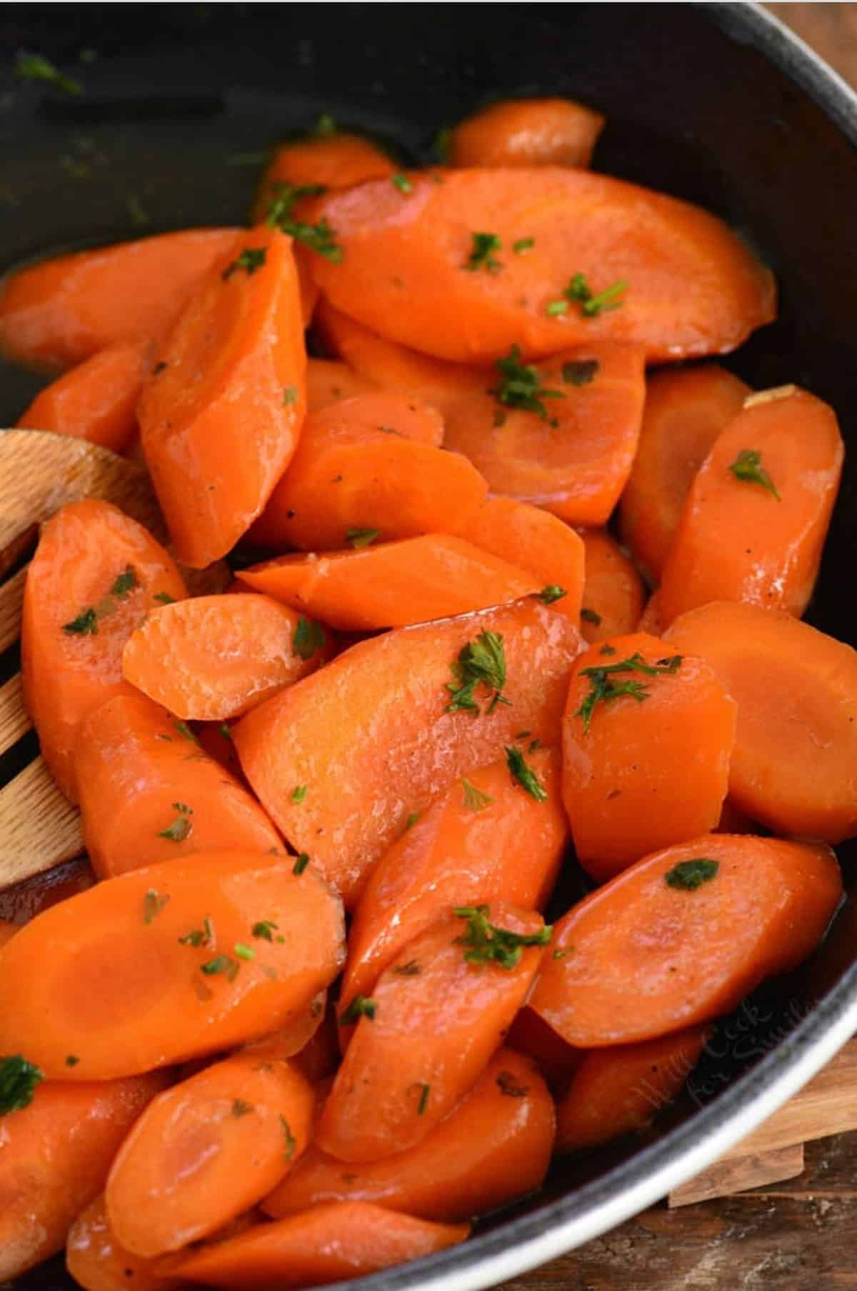 honey glazed carrots in a skillet sprinkled with parsley.