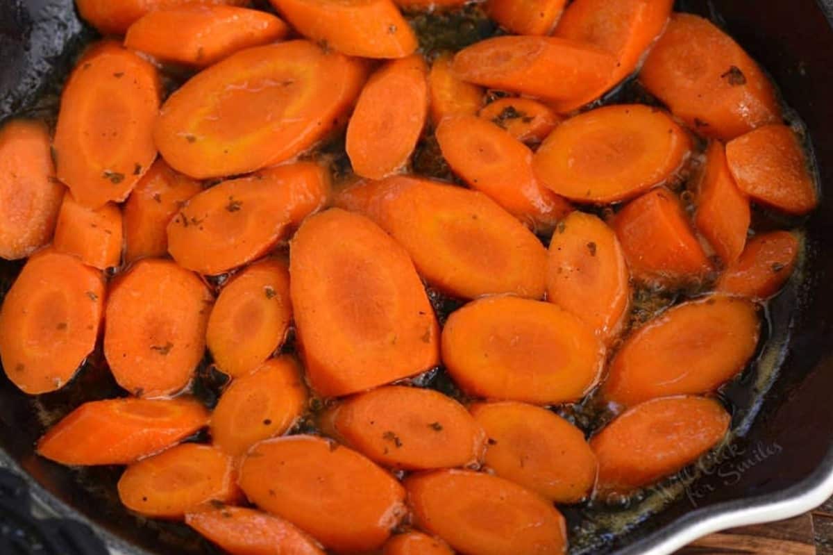 sliced carrots simmering in honey and butter in the skillet.