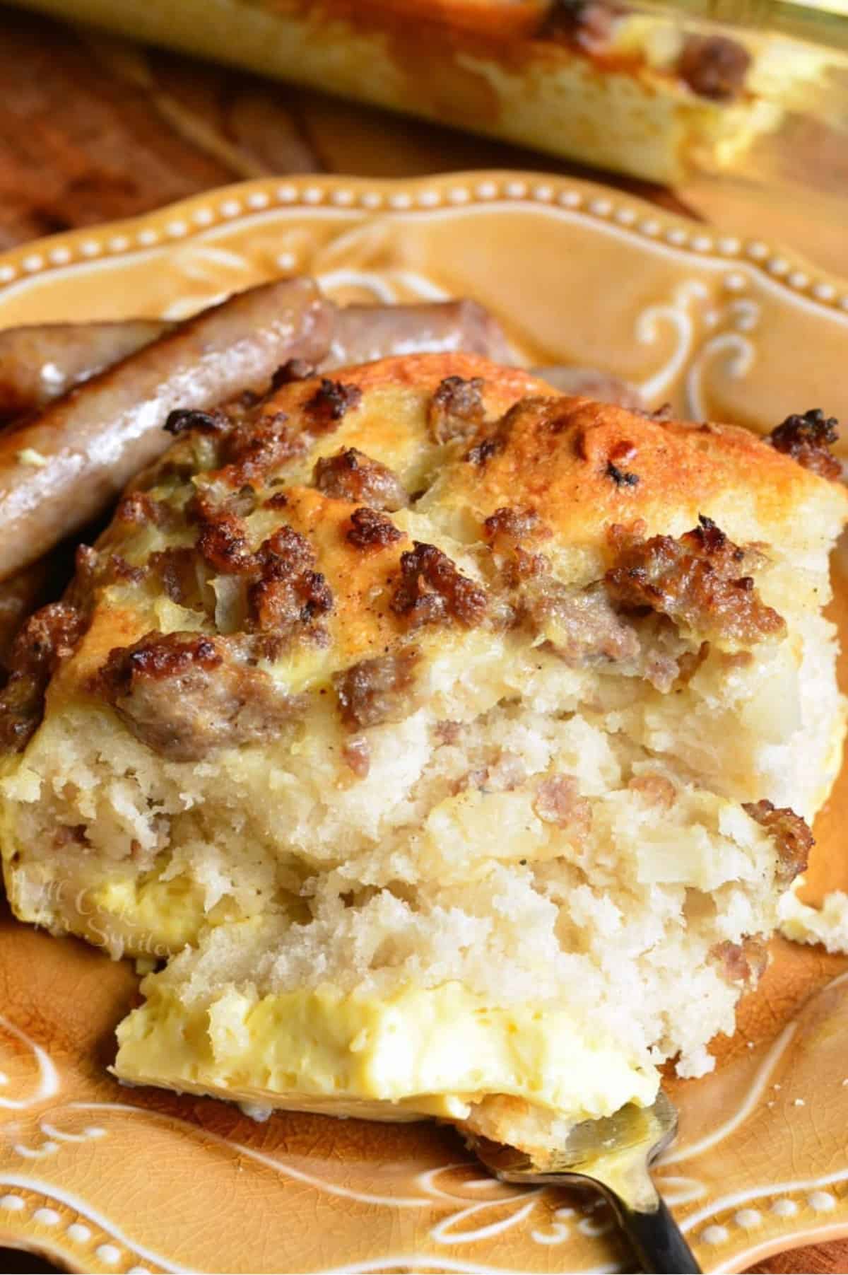 piece of sausage breakfast casserole on a plate with sausage on the side and bite on a fork.