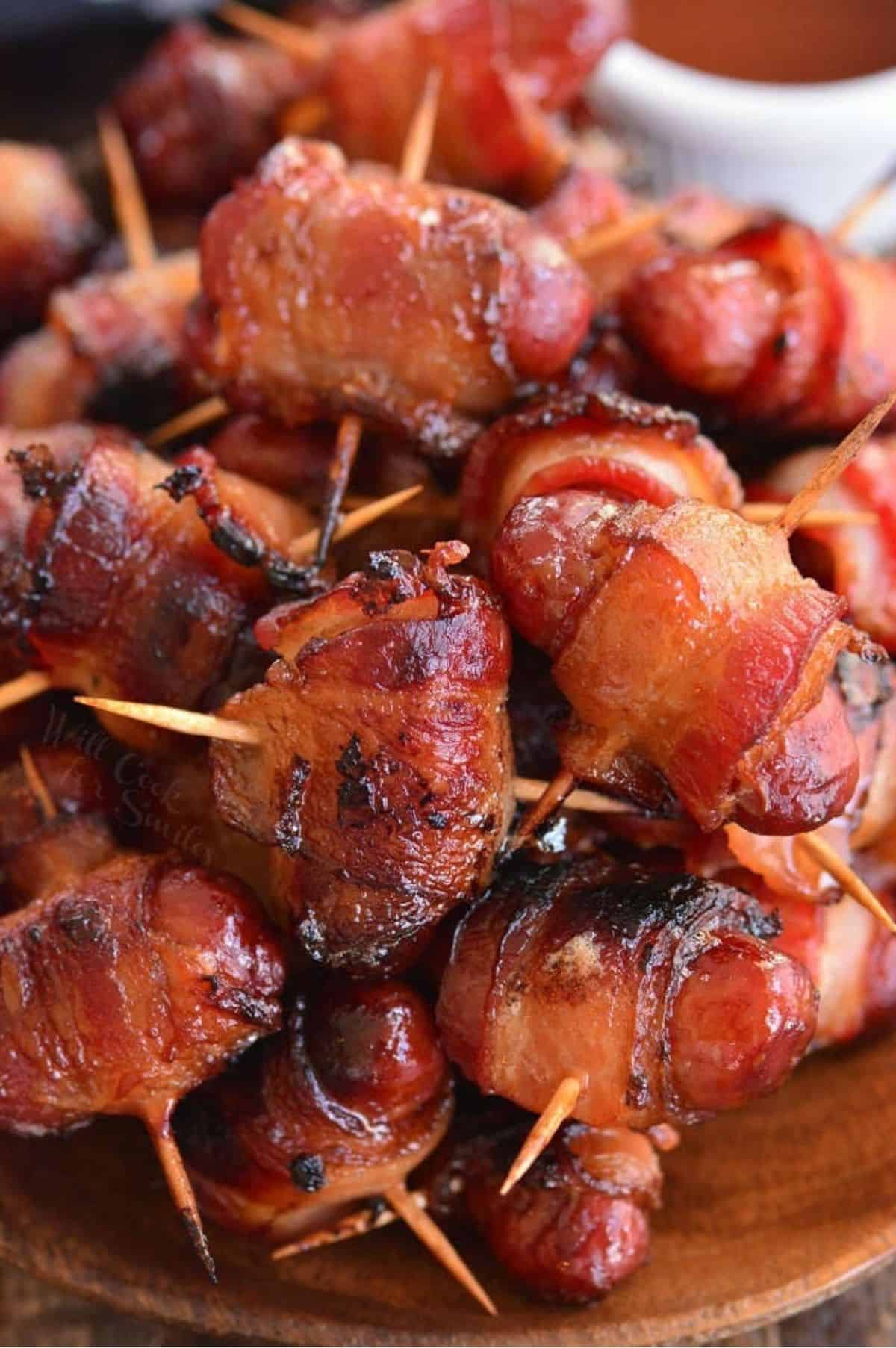 crispy bacon wrapped little smokies sausages on a wooden plate.
