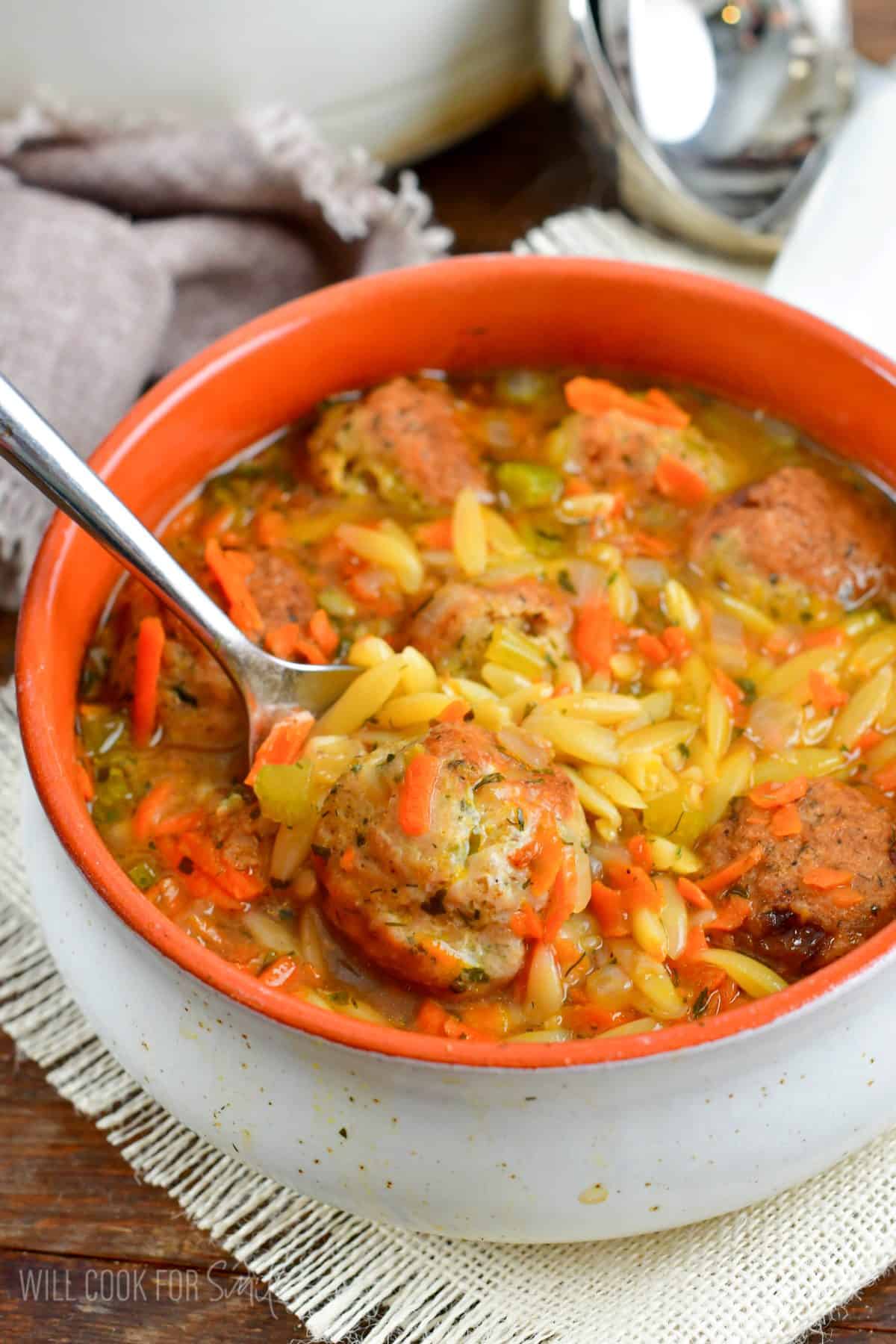 chicken meatball and orzo soup with a spoon scooping some out.