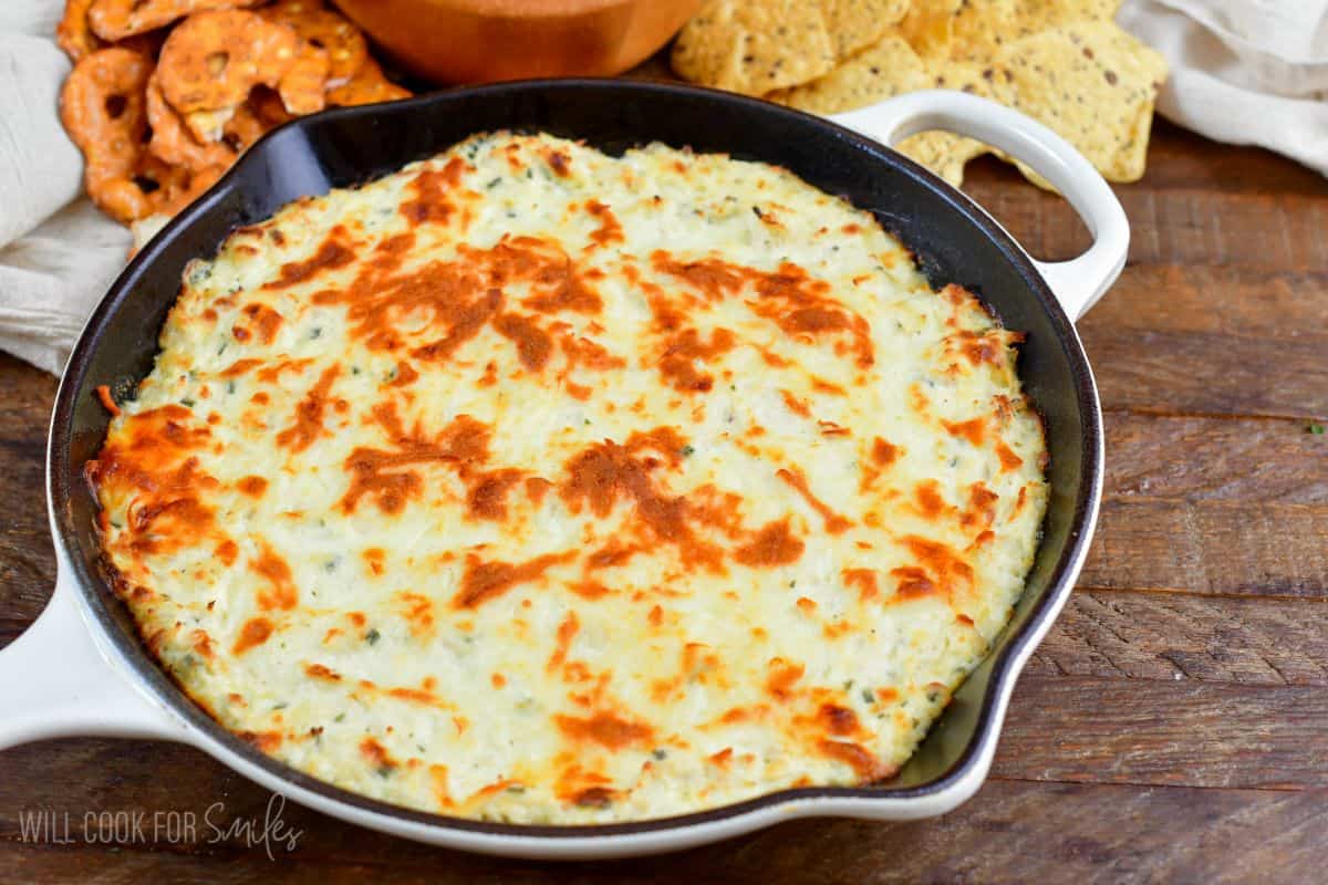 baked chicken ranch dip in a skillet next to a bowl of chips.