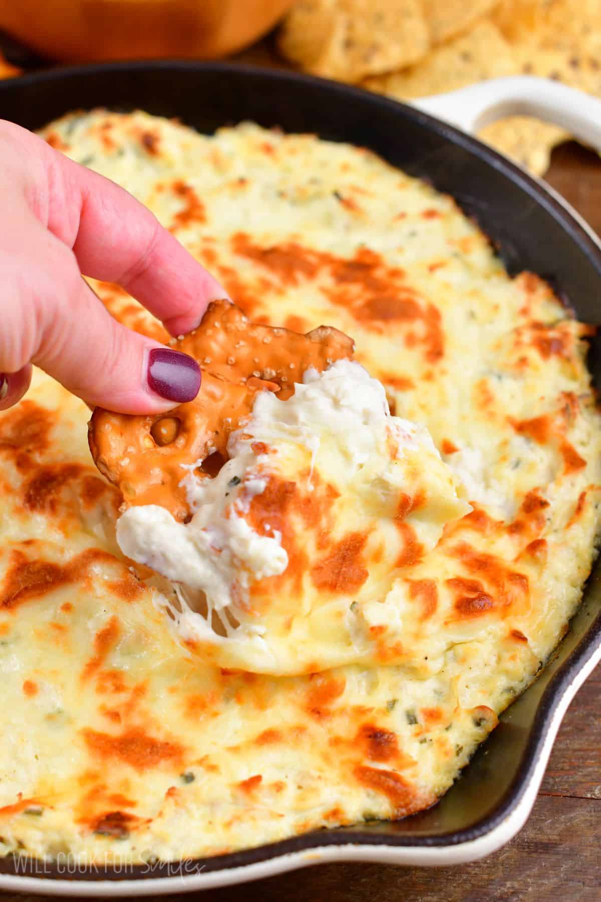 dipping into the warm chicken ranch dip with a pretzel chip.