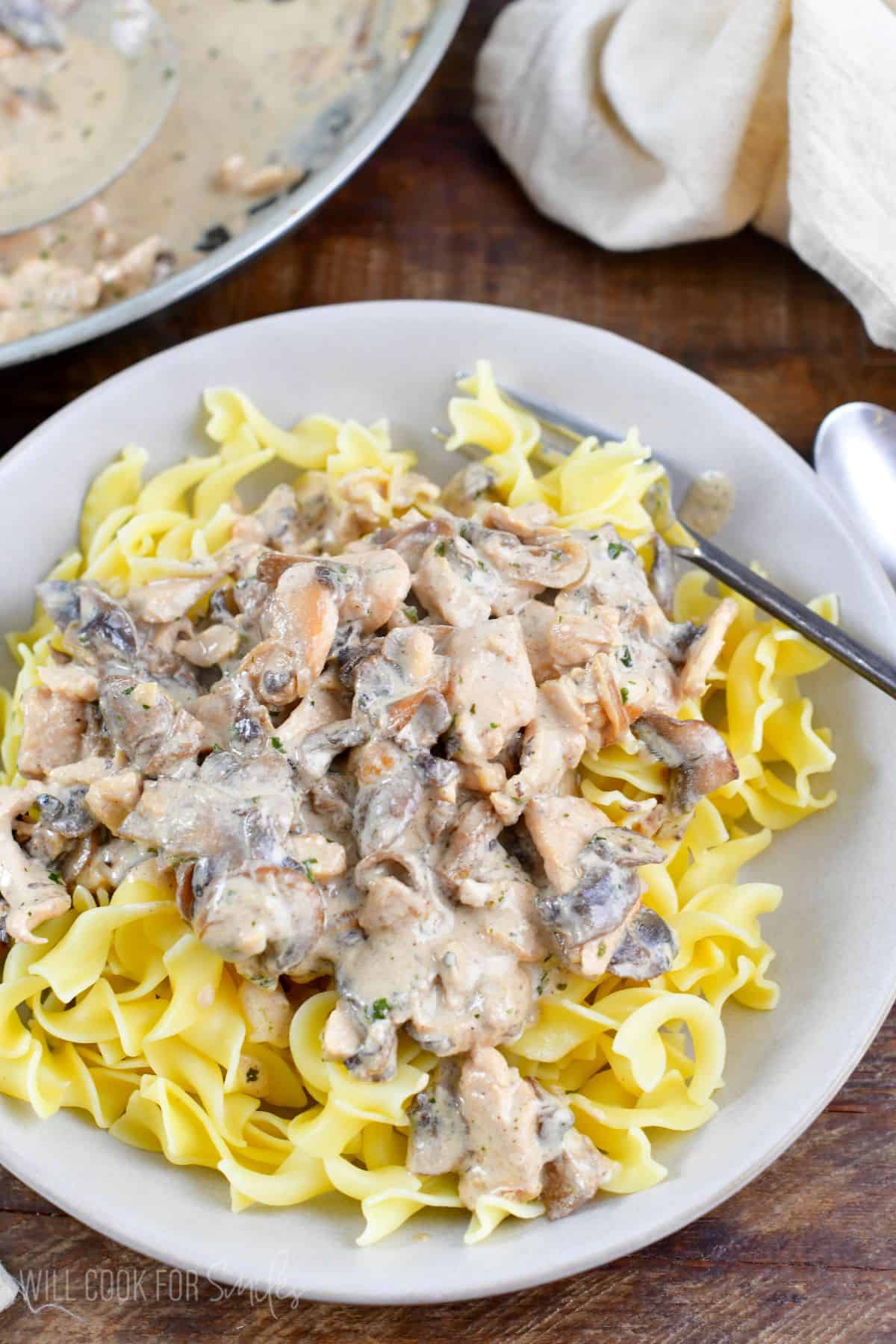 Chicken Stroganoff on top of noodles in a bowl with a fork.