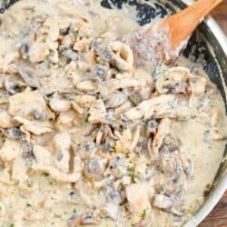 Cooked chicken stroganoff in a pan with a wooden spatula.