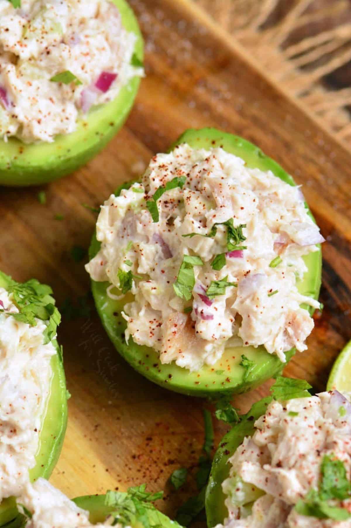 avocado half stuffed with chicken salad and some more surrounding it.