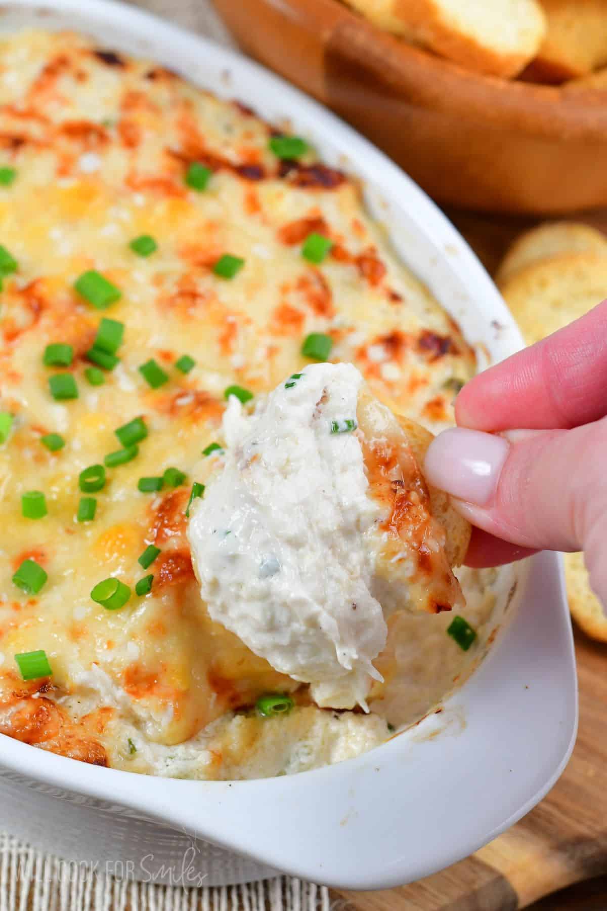 scooping out some hot baked crab dip with a bread cracker.
