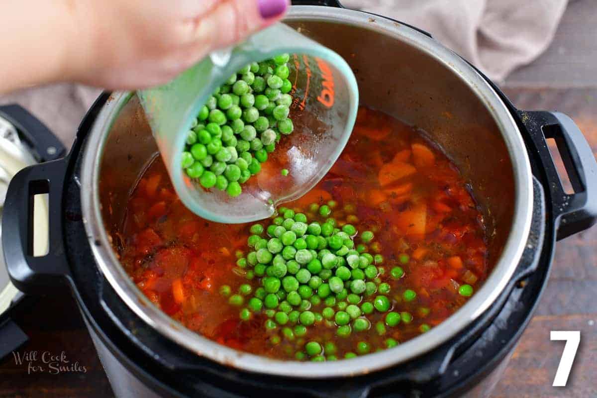 adding frozen peas to the instant pot with vegetable beef soup.