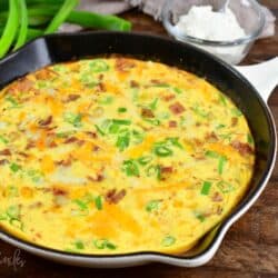a skillet with breakfast bake of potatoes, bacon, green onion and cheese.