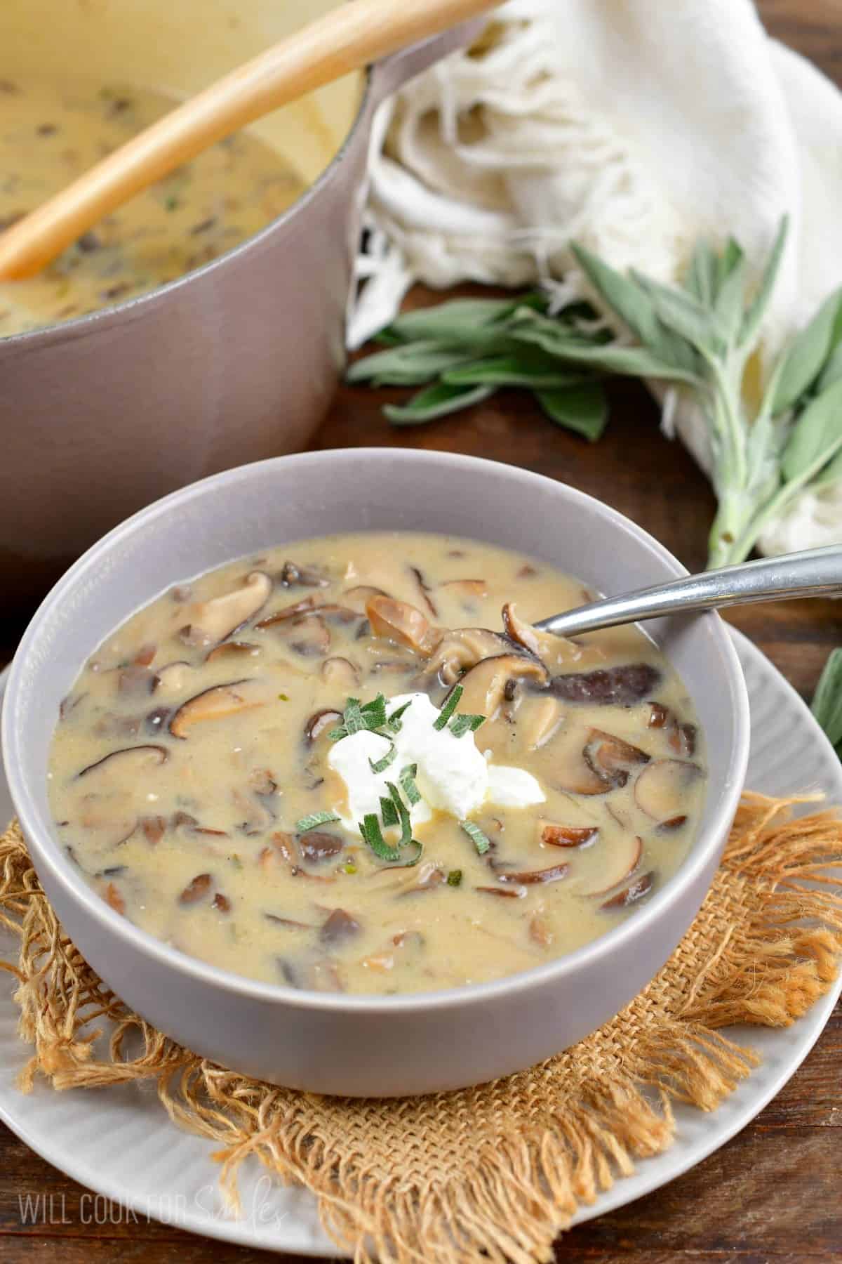 creamy mushroom soup topped with sour cream in a grey bowl with a spoon.