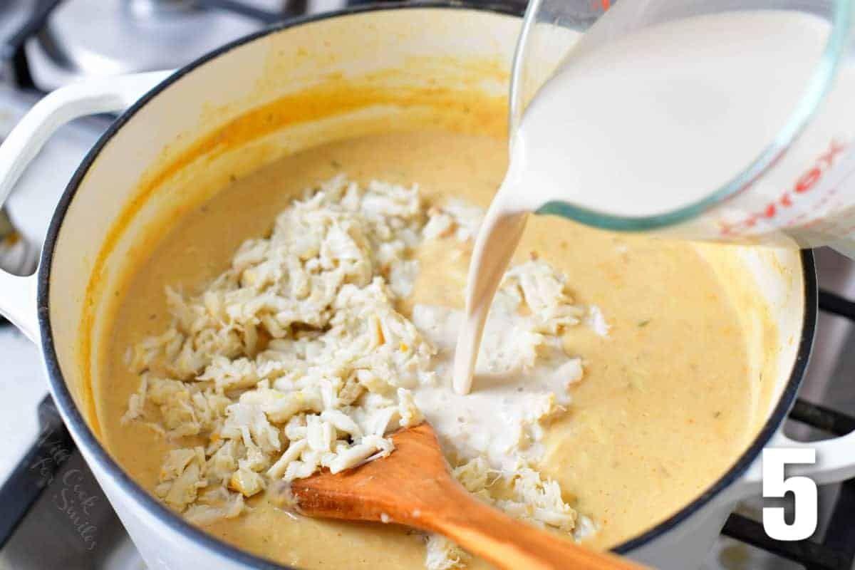 adding cream and remaining crab to the she crab soup in a pot.