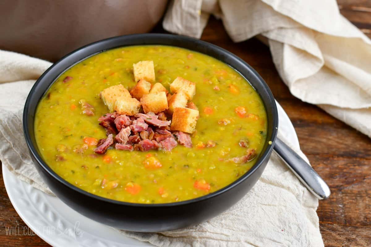 split pea soup in a bowl sitting on top of a linen napkin.