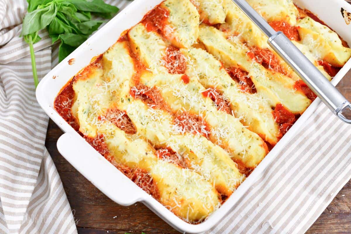 rows of stuffed shells in marinara sauce in a white baking dish.