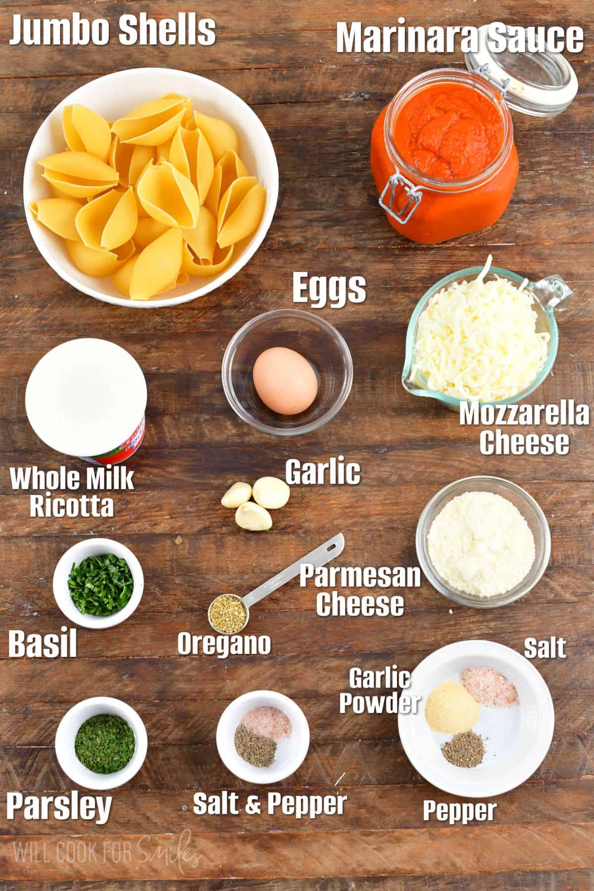 labeled ingredients to make stuffed shells on the wooden background.