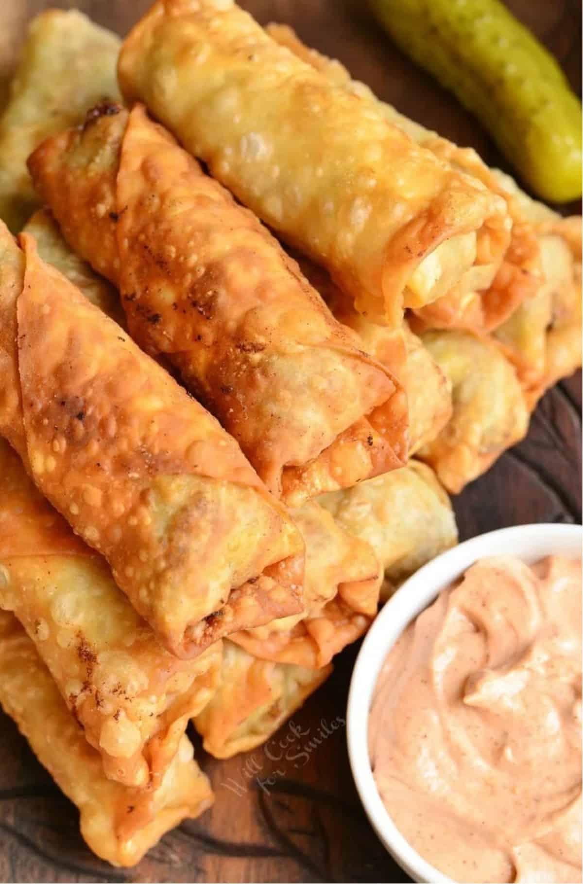 fried cheeseburger egg rolls stacked next to a dip.