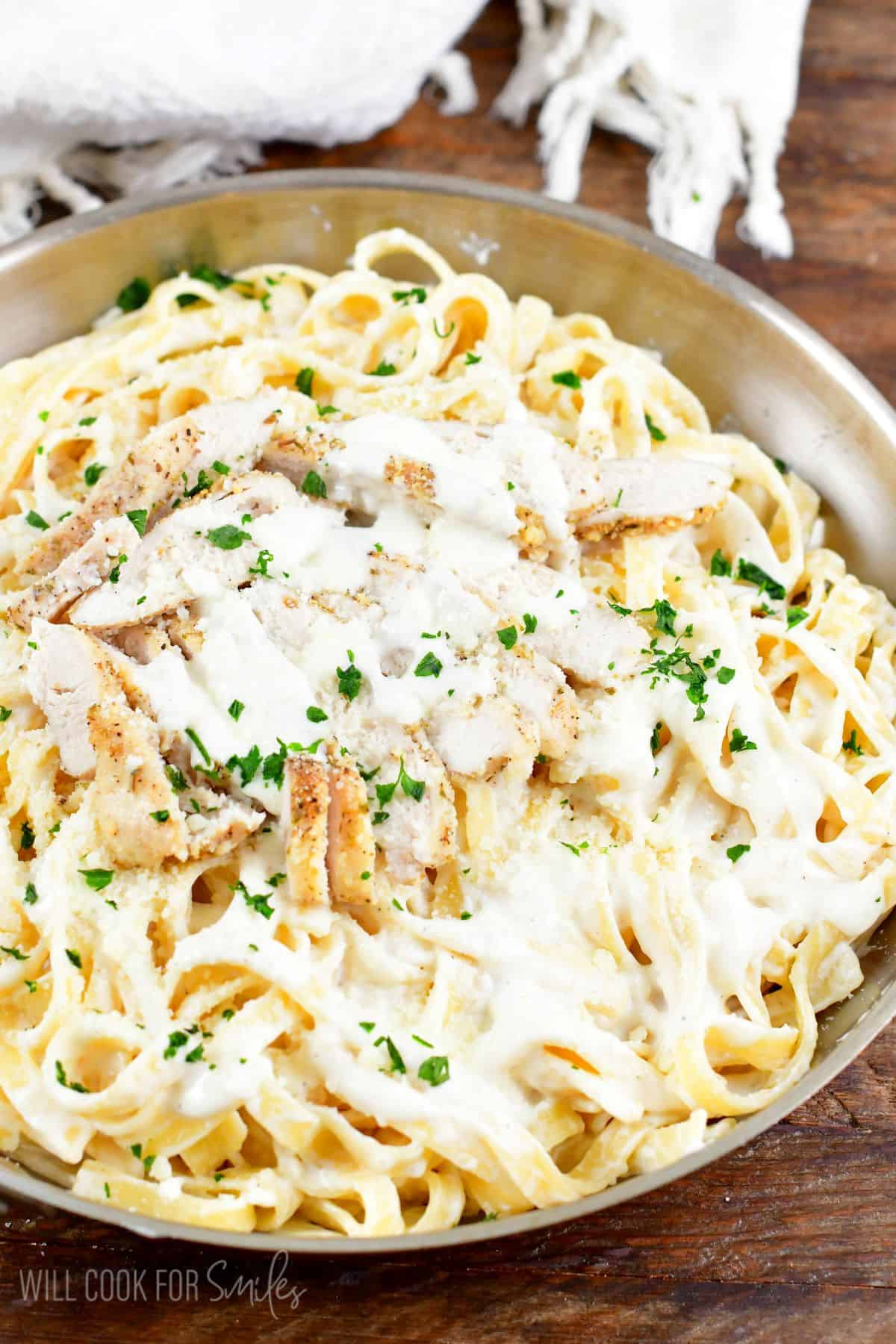 Chicken alfredo in a pan on a wood surface.