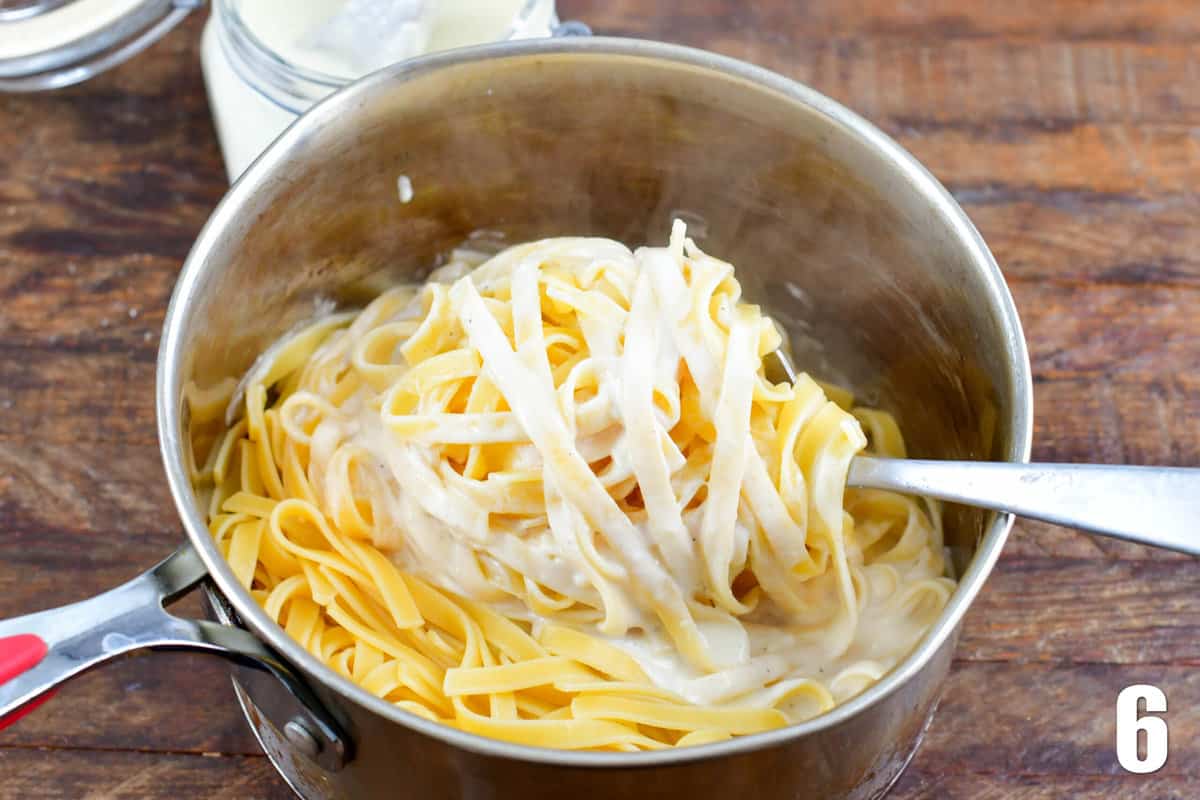 Mixing pasta and sauce together with a spoon.