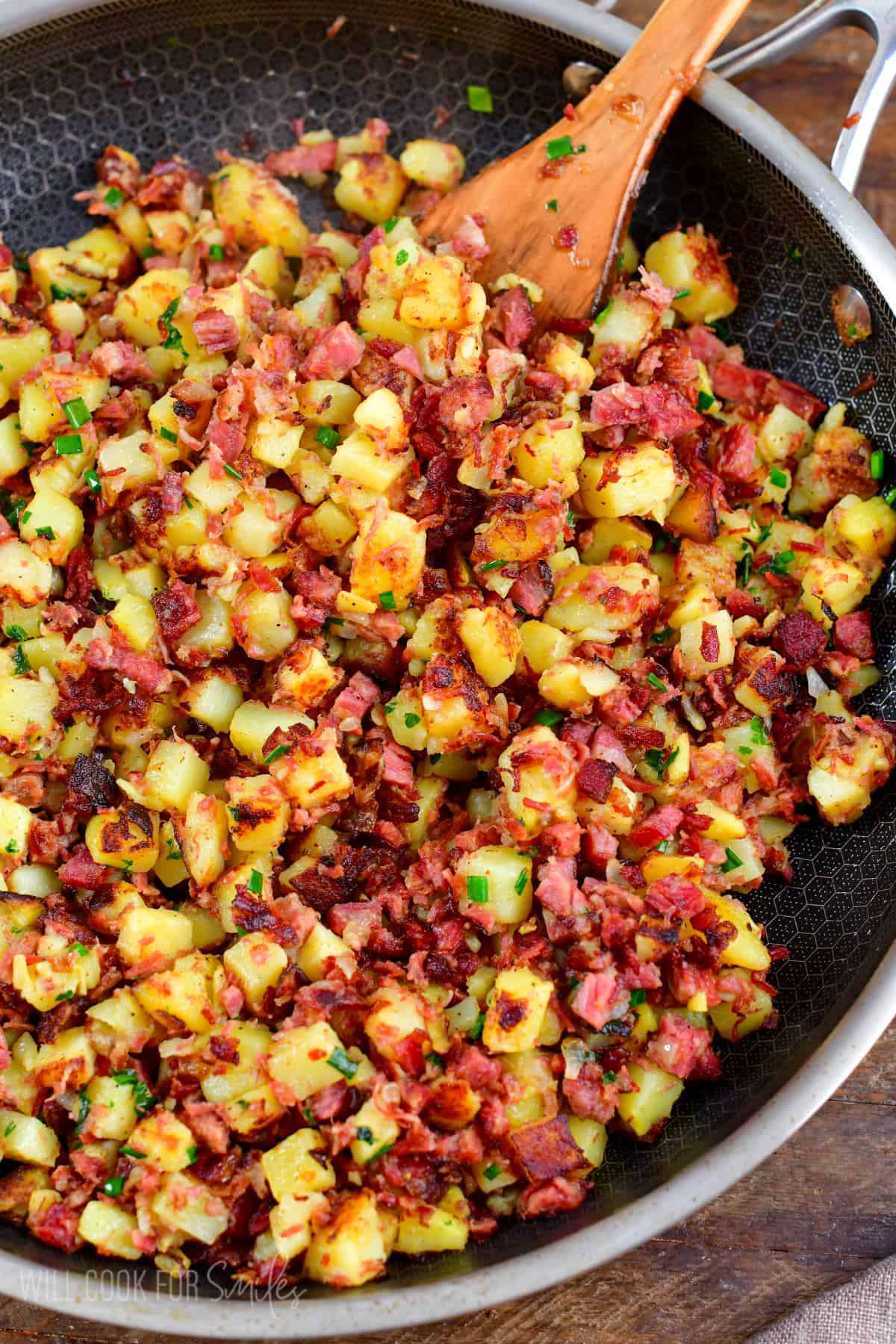 Corned Beef in a pan with a wooden spoon on a wood surface.