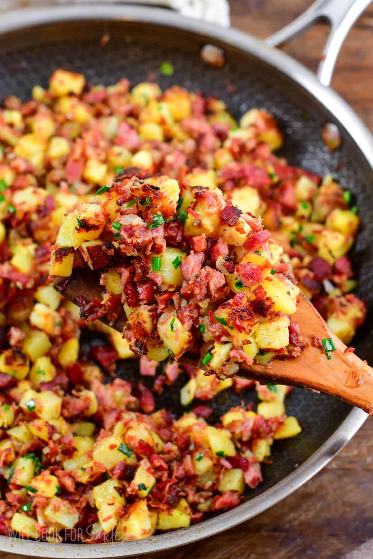 Scooping corn beef hash out of a pan.
