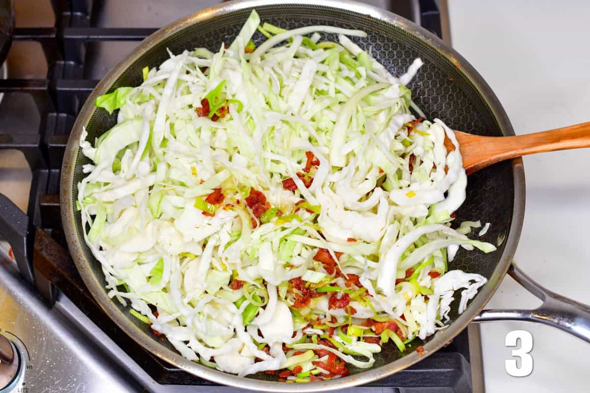 adding cabbage to the pan of bacon and leeks and stiring with a wooden spoon.