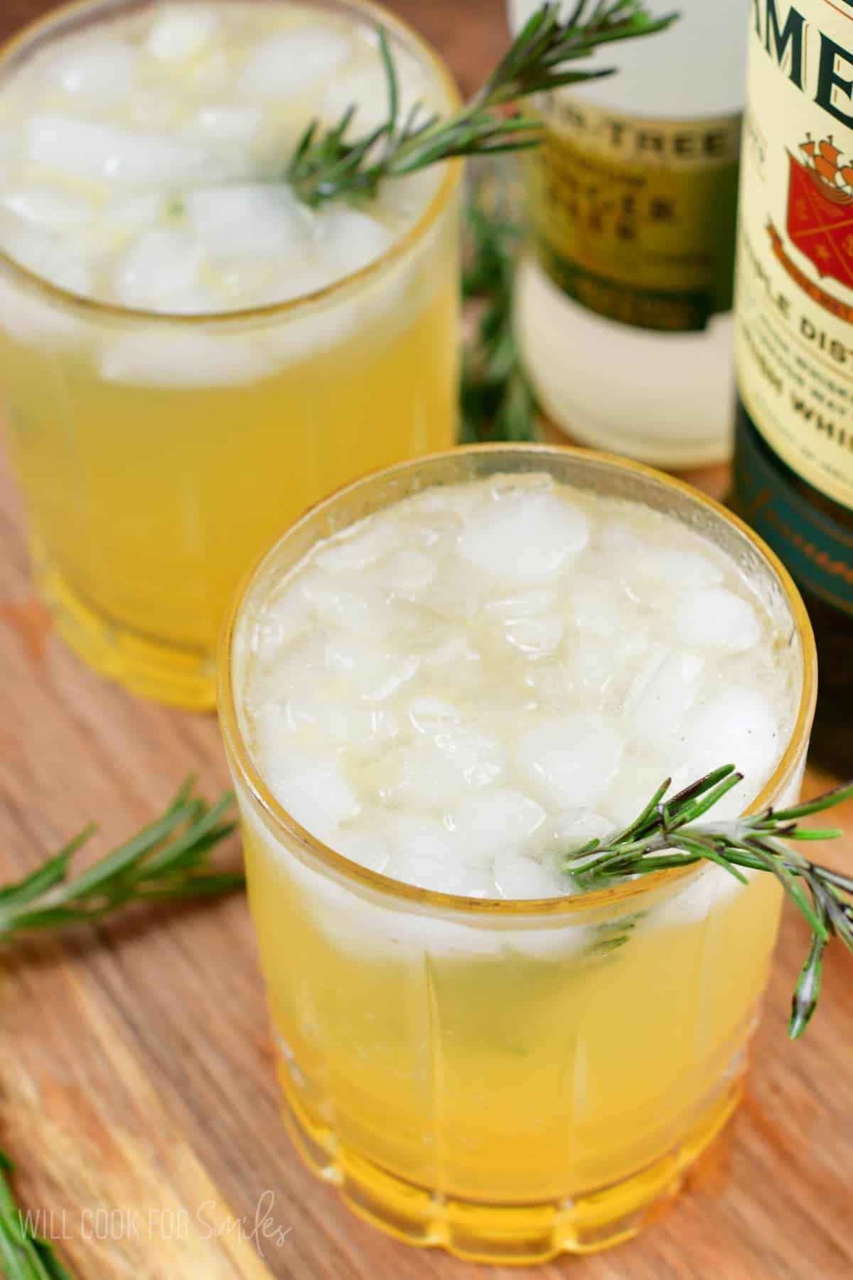 two Irish lemonades in a glass with ice and rosemary as garnish.