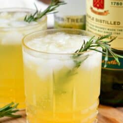 two glasses of Irish lemonade with rosemary as garnish on a wood surface.