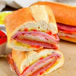 Italian sub cut in half and stacked on top of one another on parchment paper.