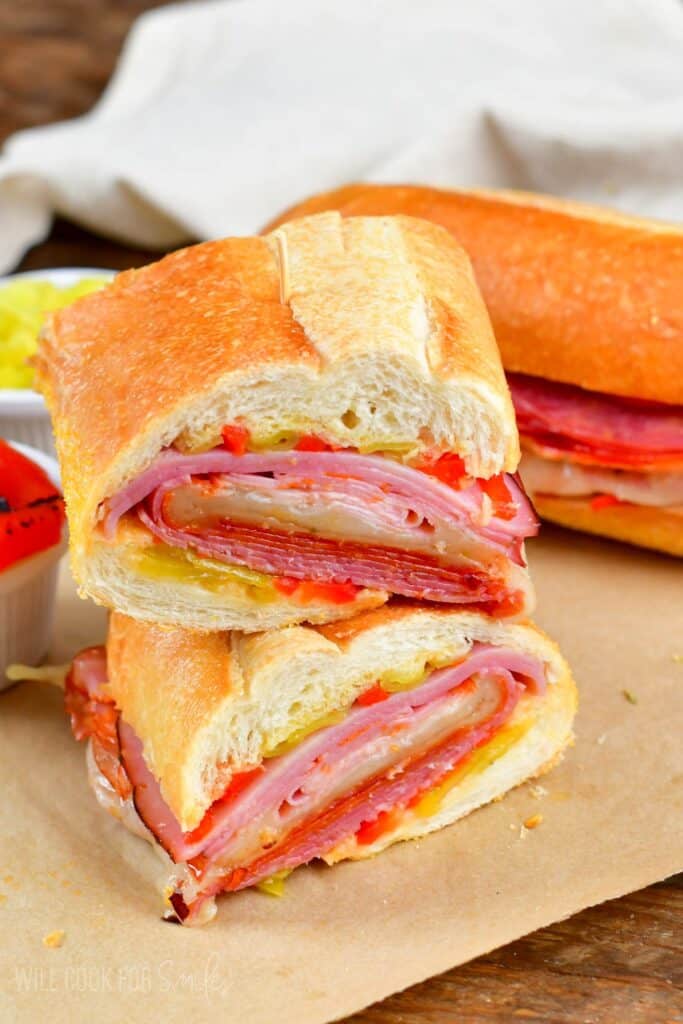 Italian sub cut in half and stacked on top of one another on parchment paper.