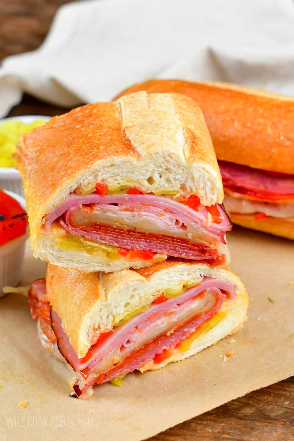 Italian sub cut in half and stacked on top of one another on parchment paper.